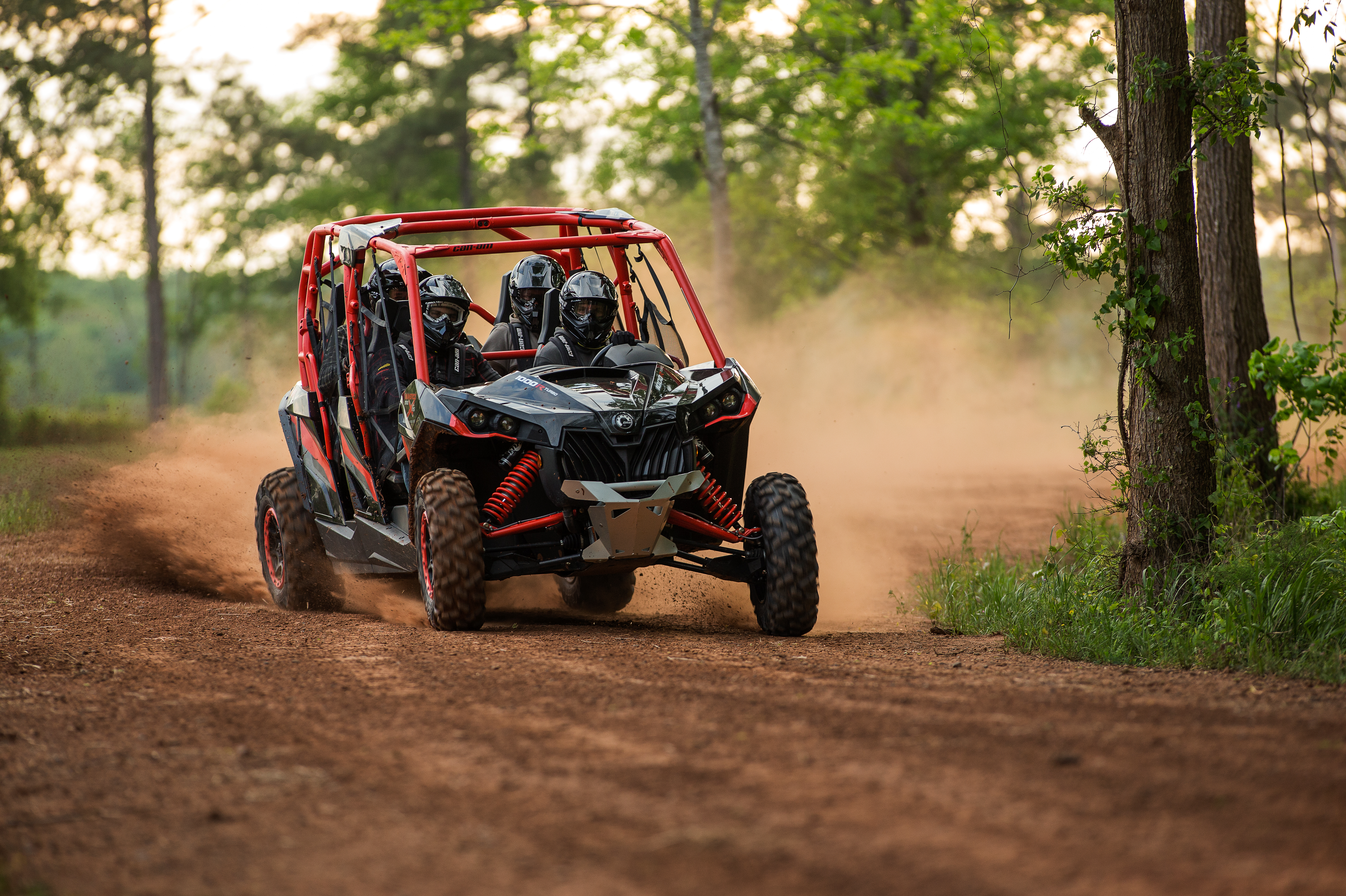 Four people riding in a can-am maverick as they traverse the forest.