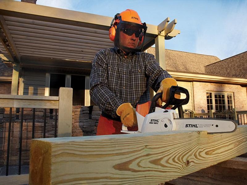 Man using a STIHL chainsaw to cut wood for his new house he's building