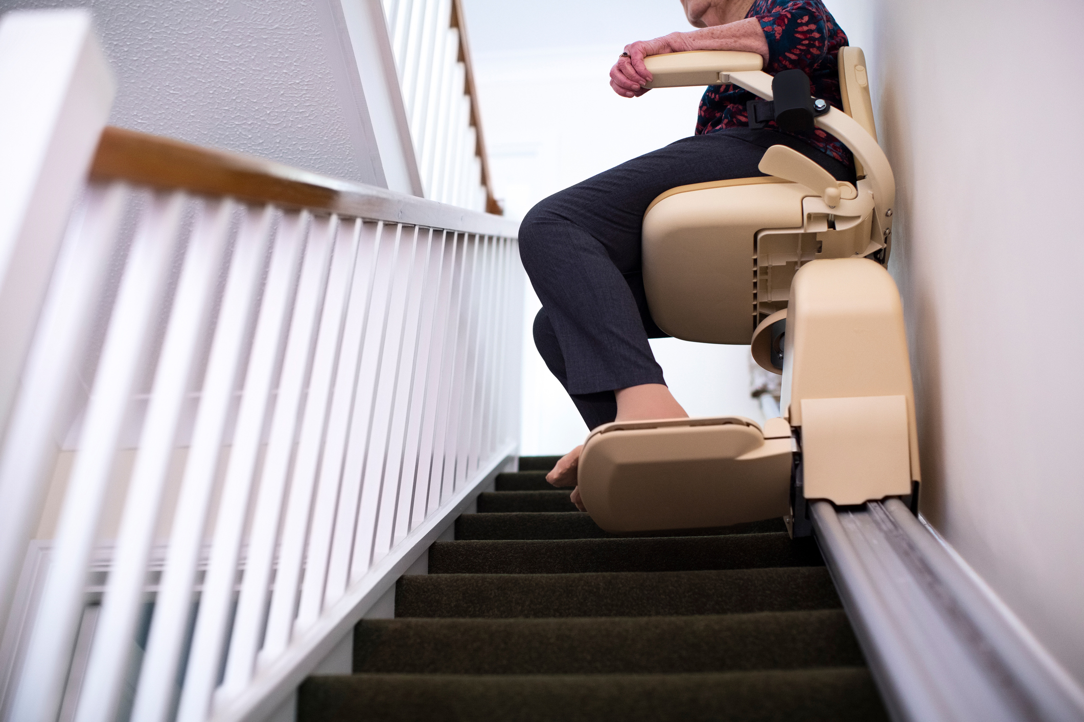 A woman uses a stair lift to get up her stairs