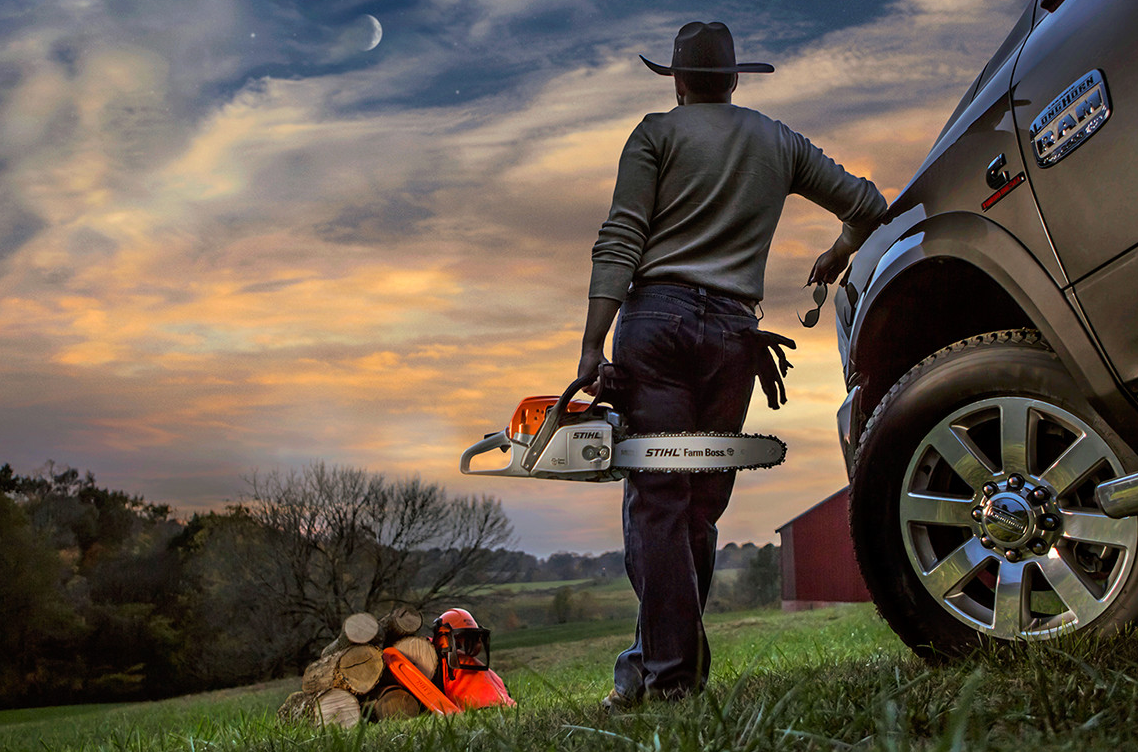 Man holding a STIHL chainsaw and leaning on a silver RAM truck