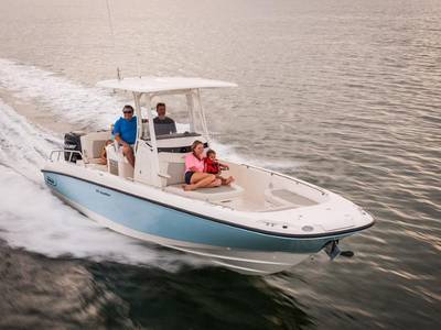 Two men behind the wheel of a Boston Whaler Dauntless® 270 boat cruise on the water with a woman and child relaxing at the bow.