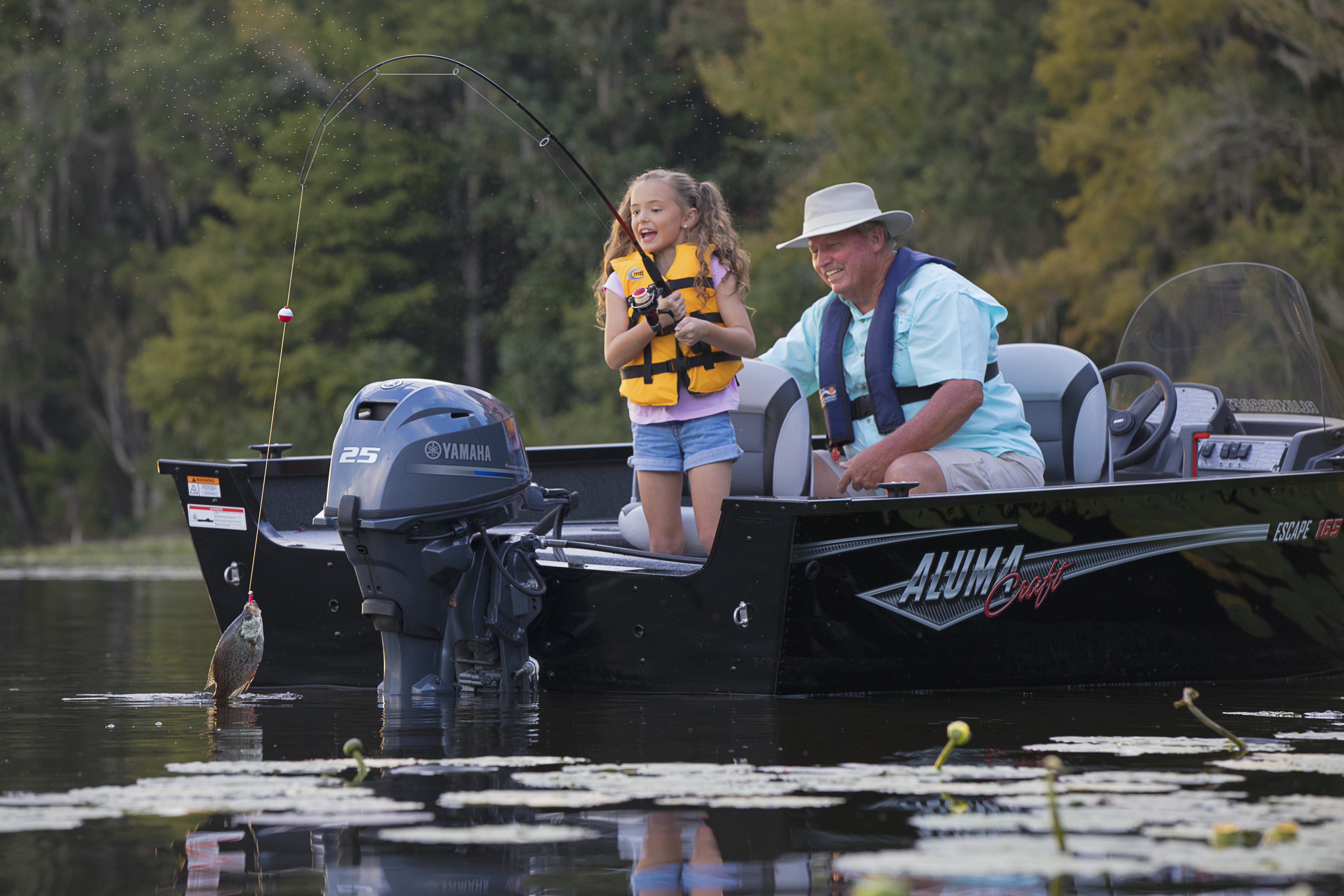 Grandpa & granddaughter fishing from Alumacraft boat with 25HP Yamaha outboard