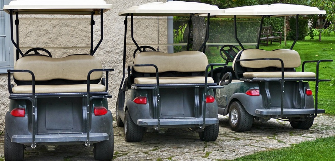 Three Club Car Golf Carts parked near a golf course