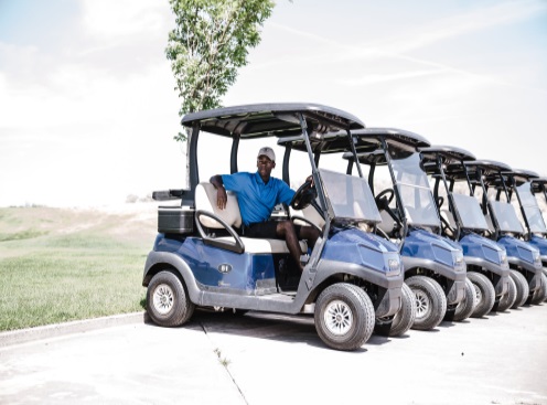 Person sitting on a Club Car golf car in a row of golf carts