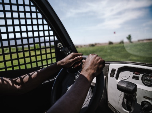 Person Driving a Golf Cart with two hands on steering wheel