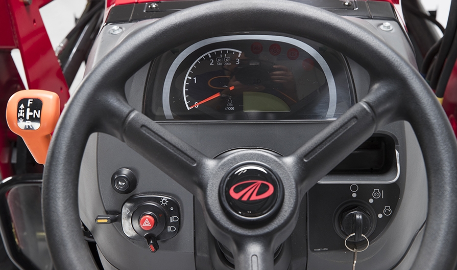 A close up of a Mahindra tractor dashboard and steering wheel.